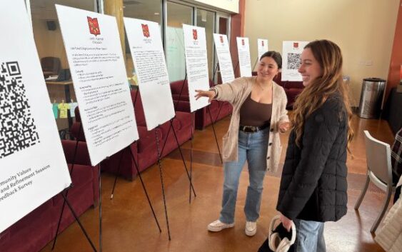 Two students look at posterboards containing the draft of the College values.