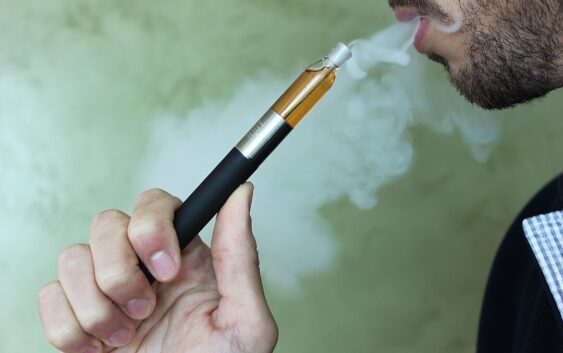 Photo of an electronic vaping pen as someone uses it.